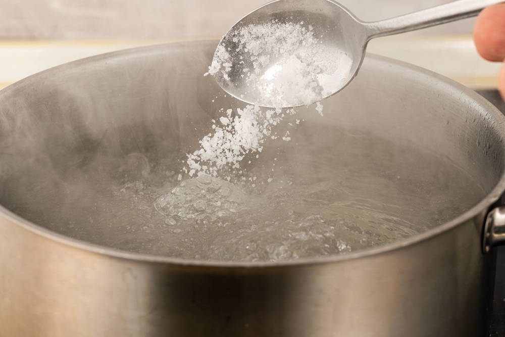 pour salt into a metal pot with boiling water with a spoon