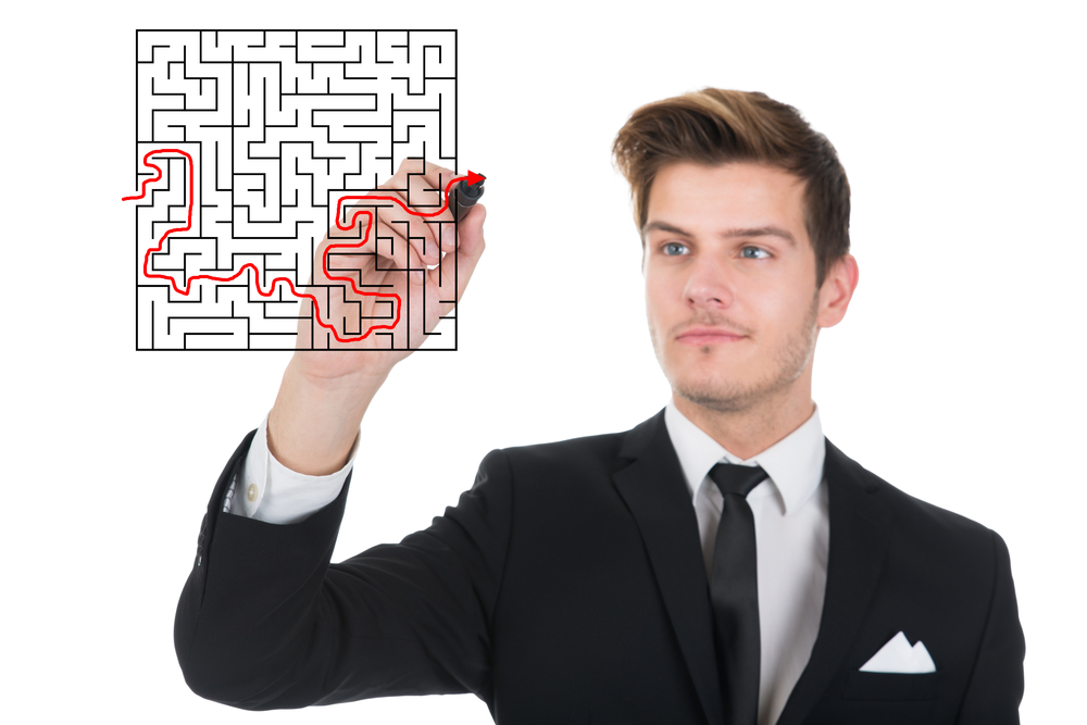 Young businessman solving maze puzzle on transparent screen over white background