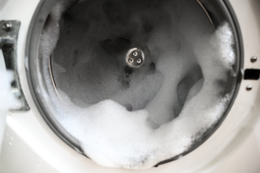 Washing machine with a lot of foam inside. Open lid.