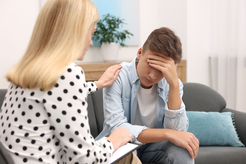Psychologist working with teenage boy in office