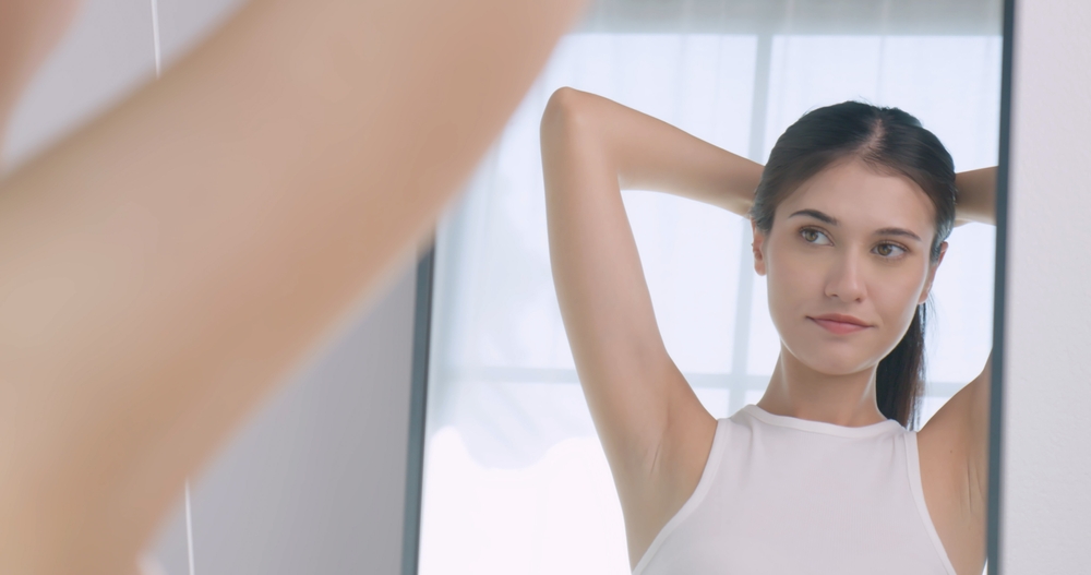 Young woman feels confident and proud of her face while standing in front of the mirror.