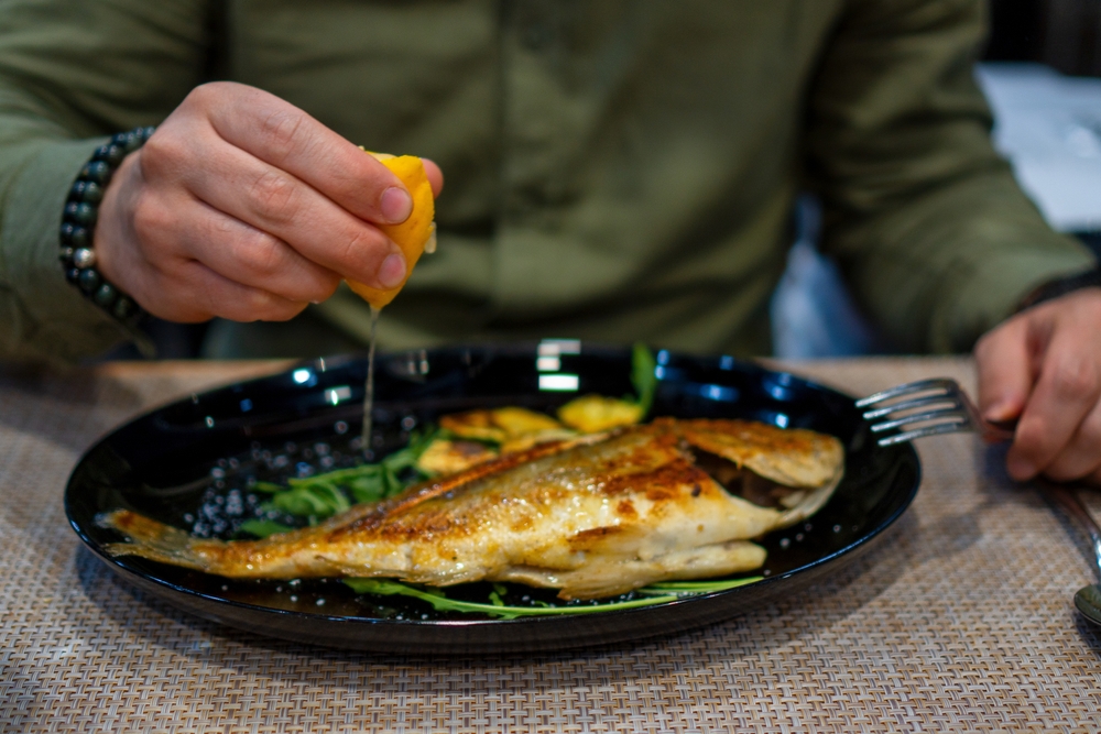A man squeezing a lemon over a dish in a restaurant in Tirana, Albania. 