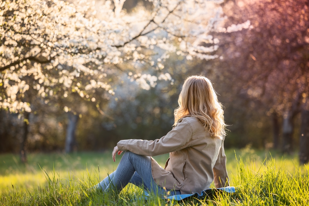 Hello Spring. Relaxed woman enjoying sunny day in blooming garden. Contemplation outdoors