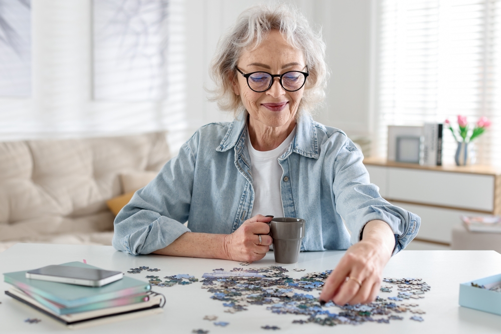 woman putting together puzzle while holding coffee cup