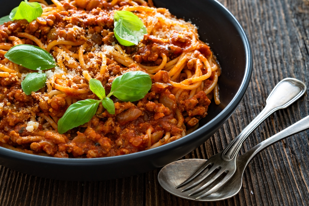 Spaghetti con ragù alla bolognese - pasta with minced meat and tomato sauce on wooden table
