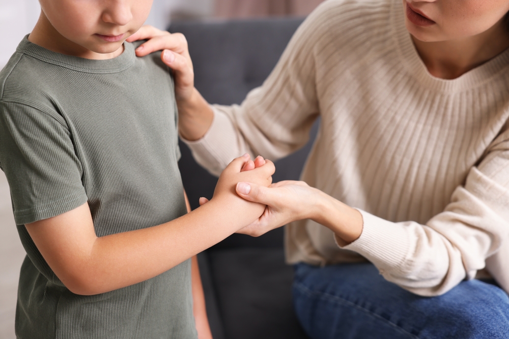 Mother supporting her upset son at home, closeup