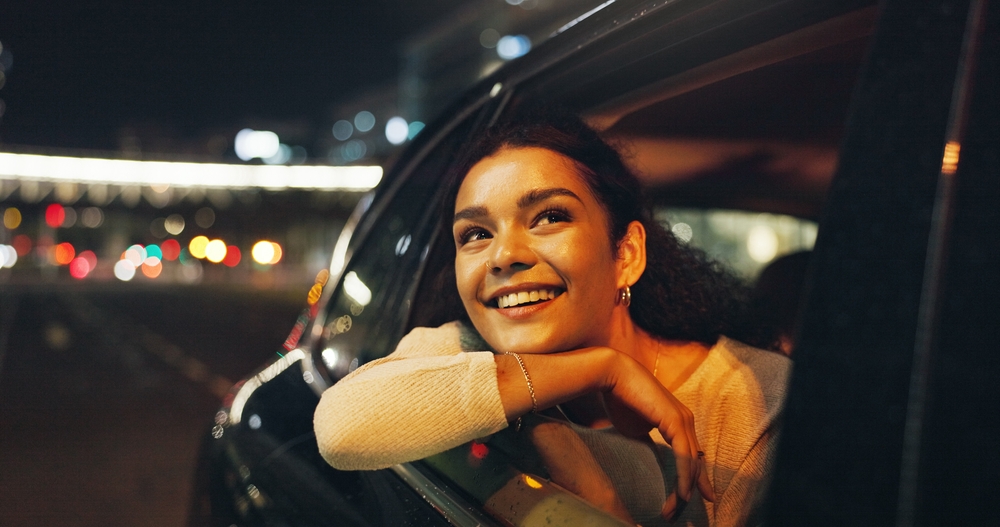 Happy, woman and window of vehicle at night for travel, sightseeing city and tourism holiday. Smile, passenger and thinking in car for fresh air, adventure trip and nightlife view for evening journey