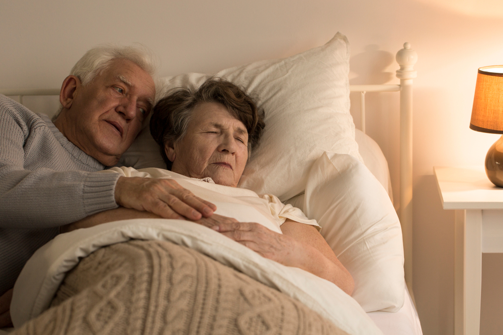 Senior man taking care of his dying wife suffering from pain at home