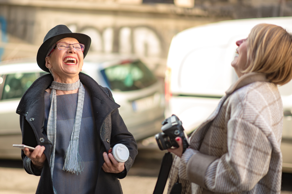 Classy women, two friends, talking, making jokes and having fun, urban outdoor area