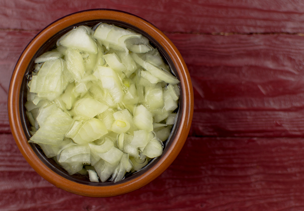 The chopped onion in a cup is filled with boiling water.