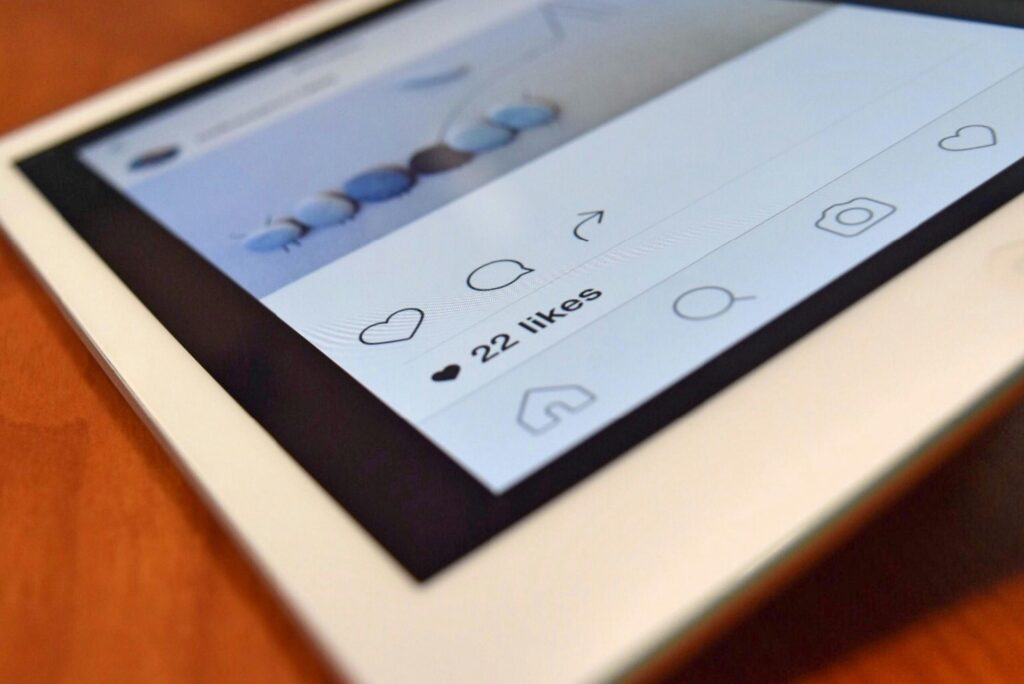 Close-up of a white tablet displaying an Instagram post with 22 likes visible under the interaction icons.