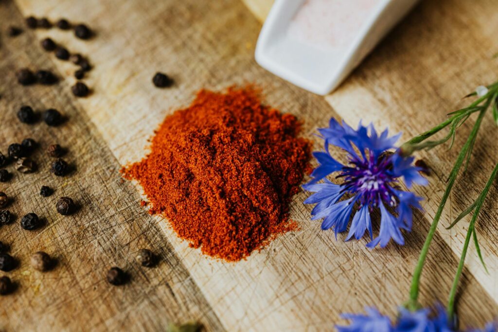 image of paprika powder on natural background next to blue flower