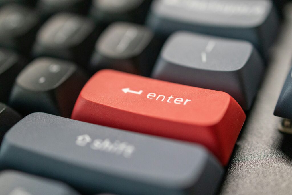 Close-up of a black computer keyboard with a bright red "Enter" key standing out among the surrounding keys.