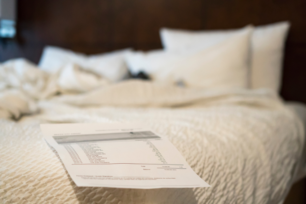 Hotel Room Service Charge Statment lays on thebed, document shows the detail of date and percentage of tax. Selective focused on % of tax charging rate.