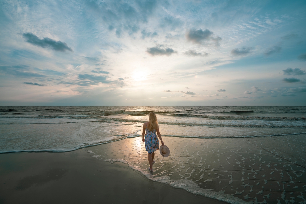 Woman standing on the beautiful beach at sunrise. Girl relaxing on moody beach. Jekyll Island, Georgia, USA.