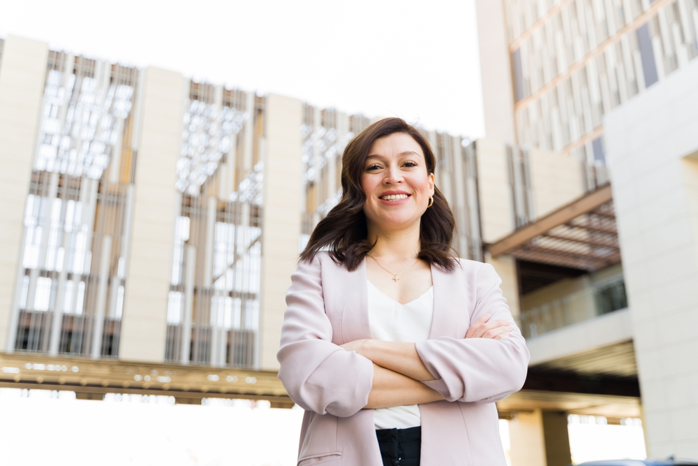 Beautiful woman with a friendly smile standing confidently outdoors with office buildings in the background, portraying a successful urban work life