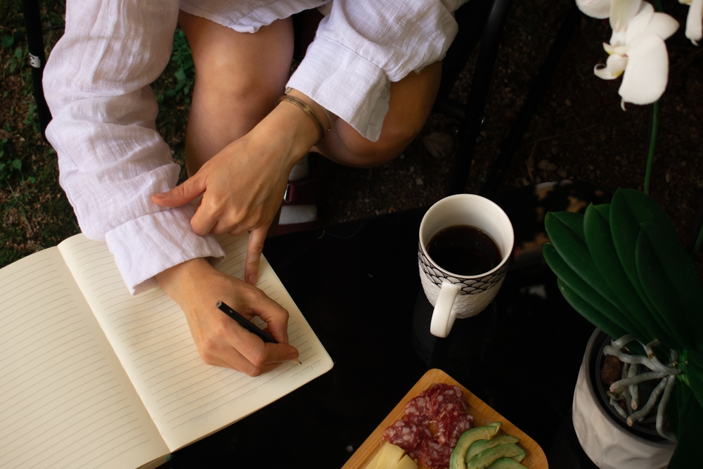 Starting the day right: journaling with a warm cup of coffee and a healthy snack amidst nature's calm. Ideal for wellness, mindfulness, or lifestyle content.