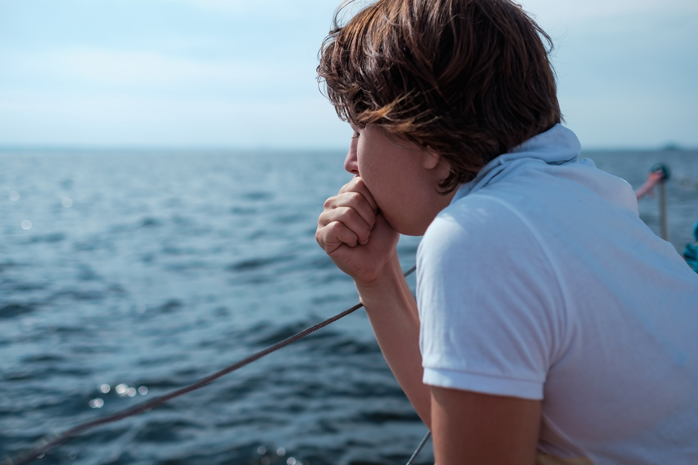 Young woman suffer from seasickness during vacation on boat
