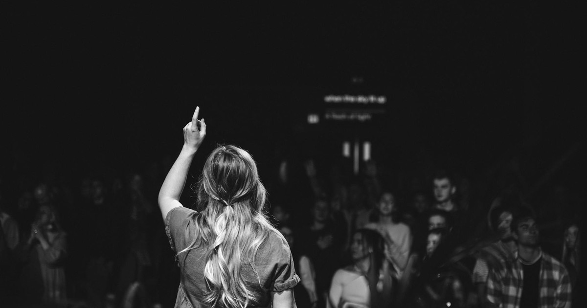 Back view of a woman on stage pointing to the audience during a concert in black and white.
