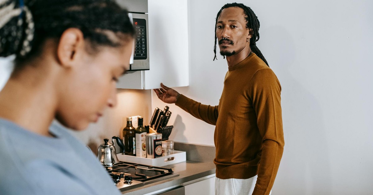 Young black couple in casual outfit standing at kitchen and arguing with each other at home