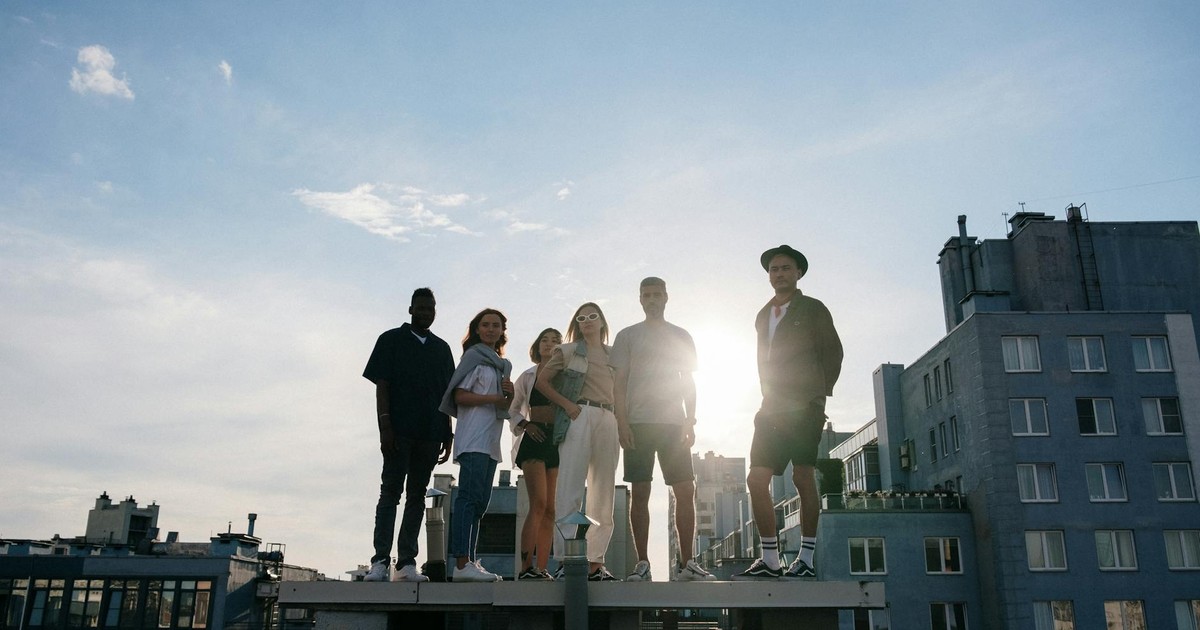 Group of young adults standing on a rooftop enjoying a sunny day, symbolizing freedom and friendship.