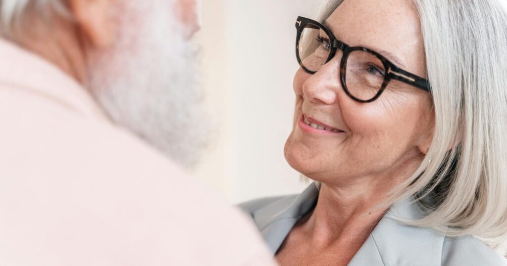 A senior couple smiling warmly at each other, highlighting love and companionship in their relationship.