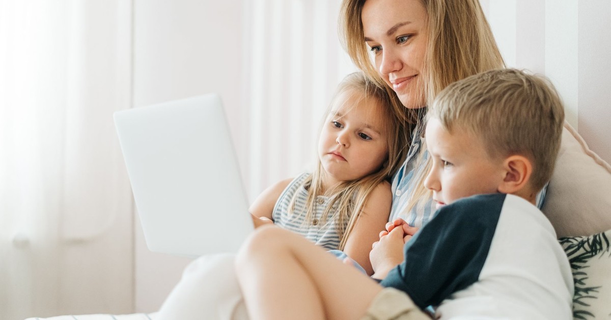 A mother spending quality time with her son and daughter, watching together on a laptop at home.