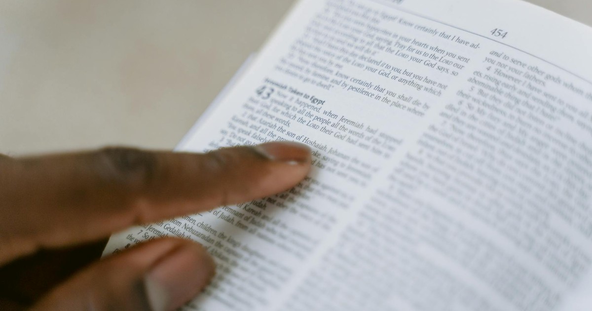 A person pointing to a passage in the Holy Bible, highlighting religious study.