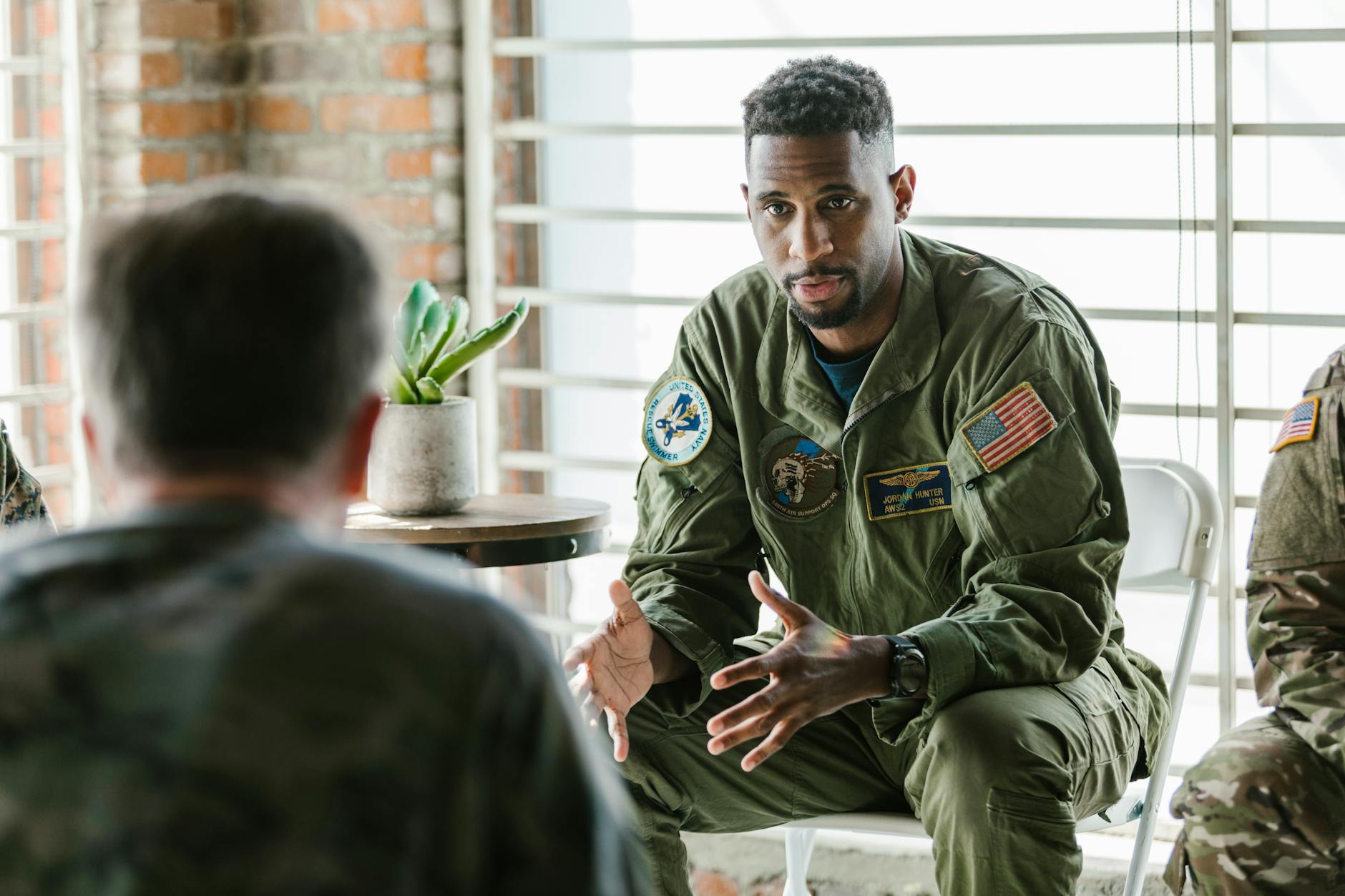 A group of military veterans participate in a supportive therapy session indoors.