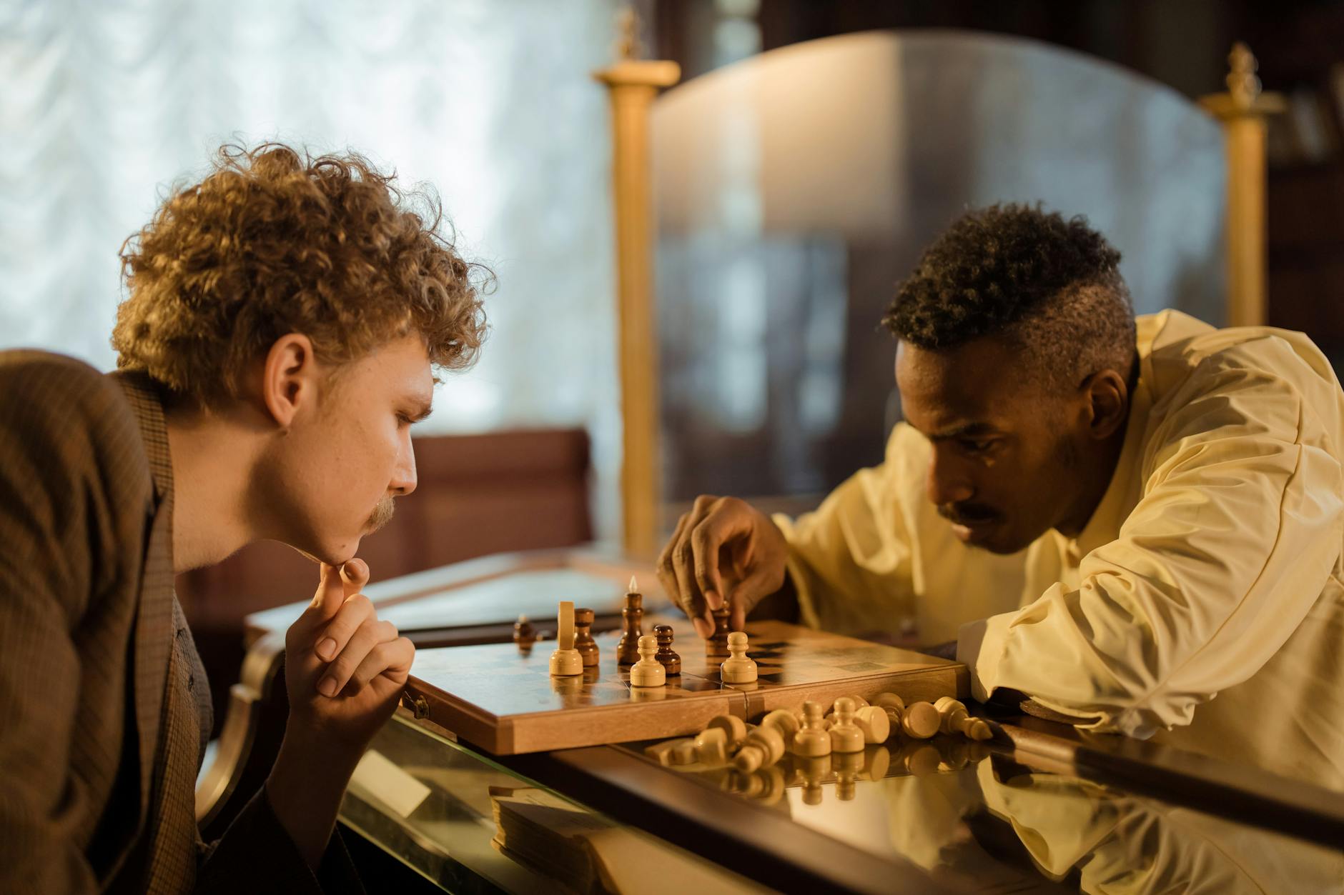 Two men focused on a chess game indoors, embodying strategy and concentration.