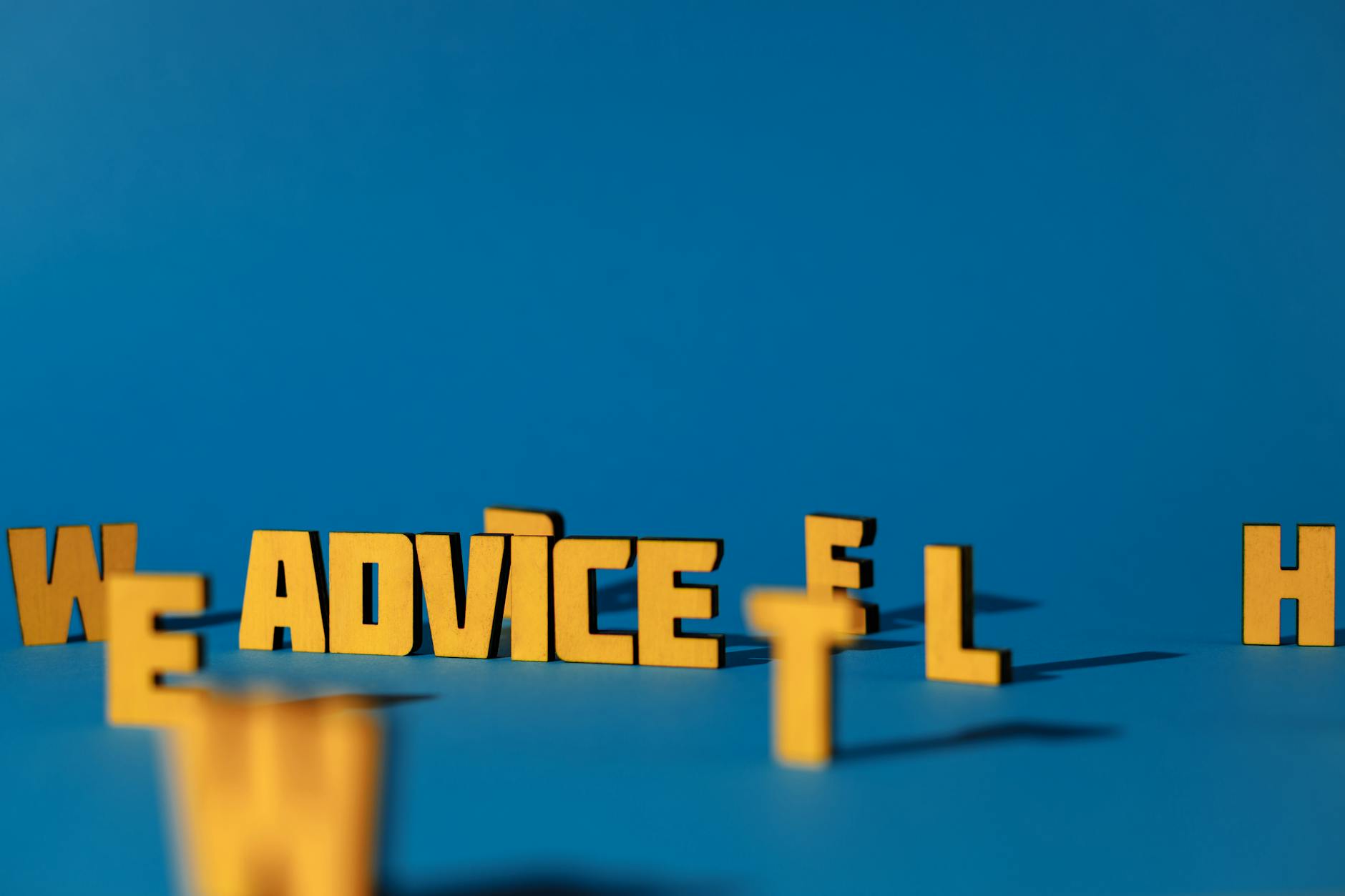 Wooden letters spelling 'Advice' on a blue background providing conceptual copyspace.