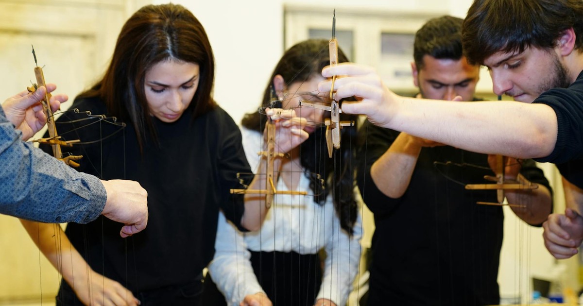 A group of young adults engaging in a puppet crafting workshop, focusing intently on their projects.