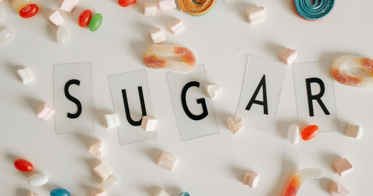 Flat lay of assorted colorful candies around the word 'SUGAR' on a white background.