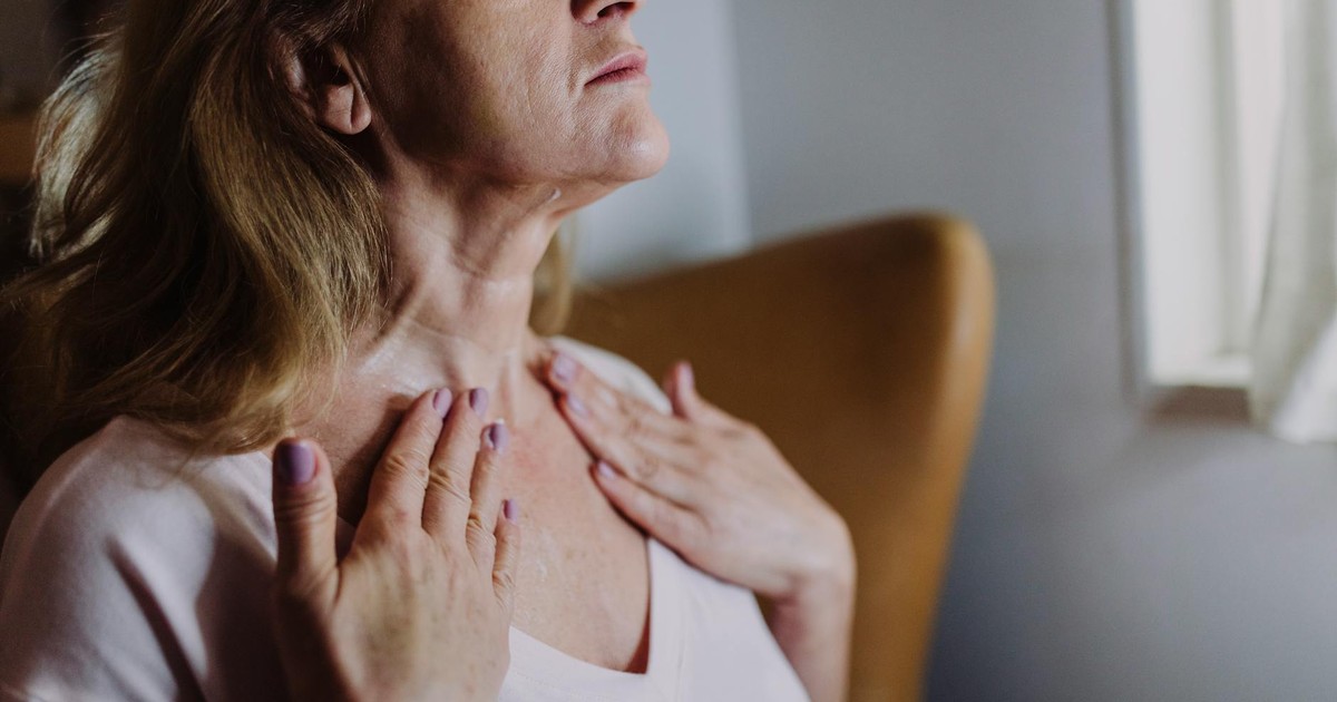 A mature woman gently massaging moisturizer into her neck, highlighting skincare routine and self-care.
