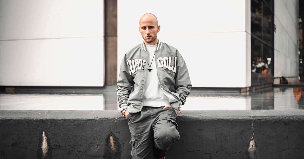 Stylish man wearing a varsity jacket and cargo pants in an urban environment.