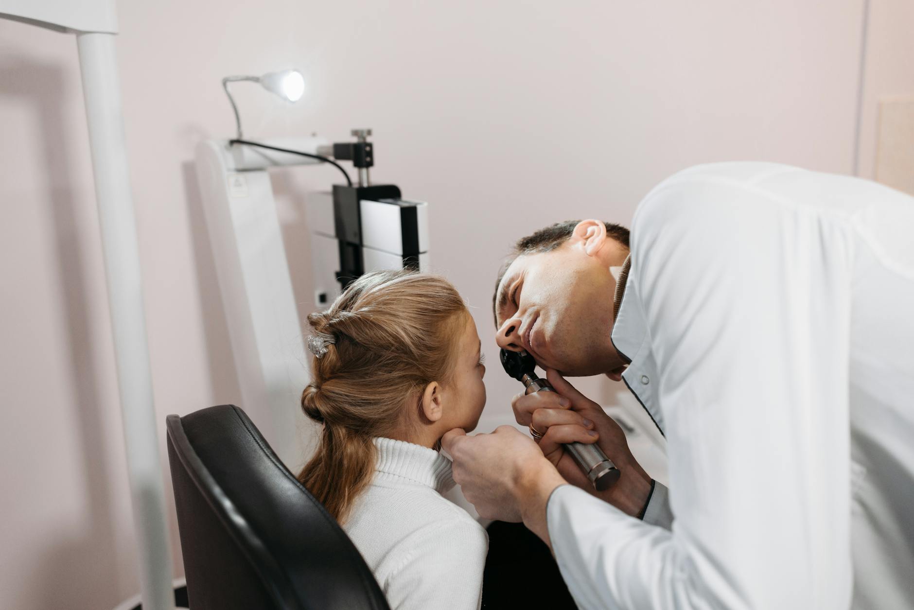 A doctor examines a young girl's ear during a medical appointment in a clinic.