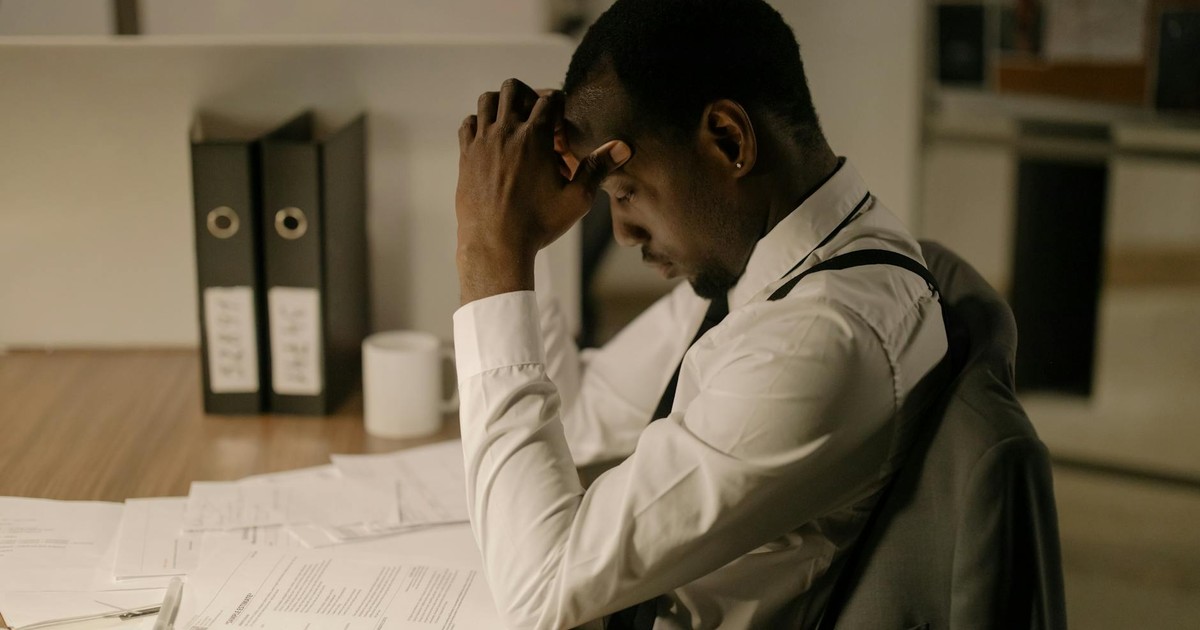An adult man in an office is concentrating on documents, reflecting stress and focus in a work environment.