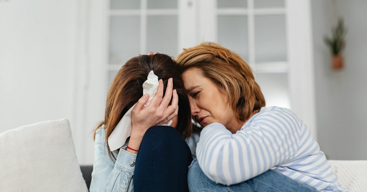 Two women share an emotional moment, conveying comfort and empathy indoors.