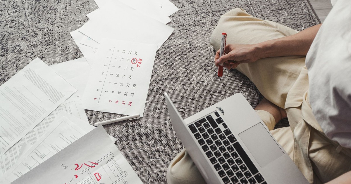 Young man working on plans with laptop and calendar, organizing tasks and schedules.