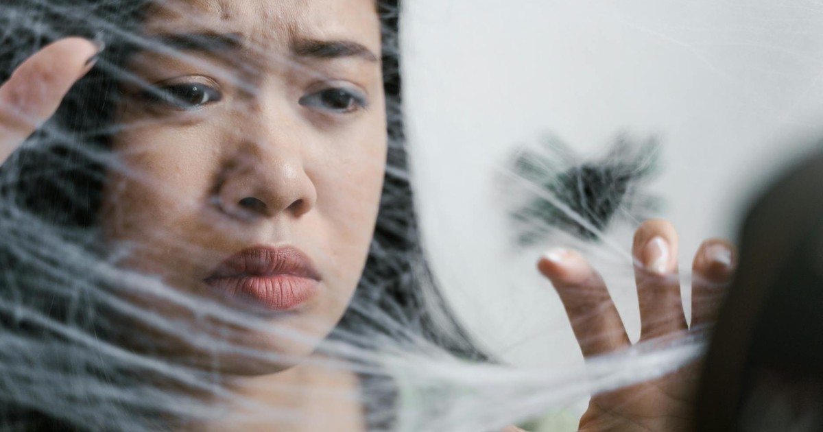 Close-up of a woman showing fear and anxiety as if trapped in a spider web.