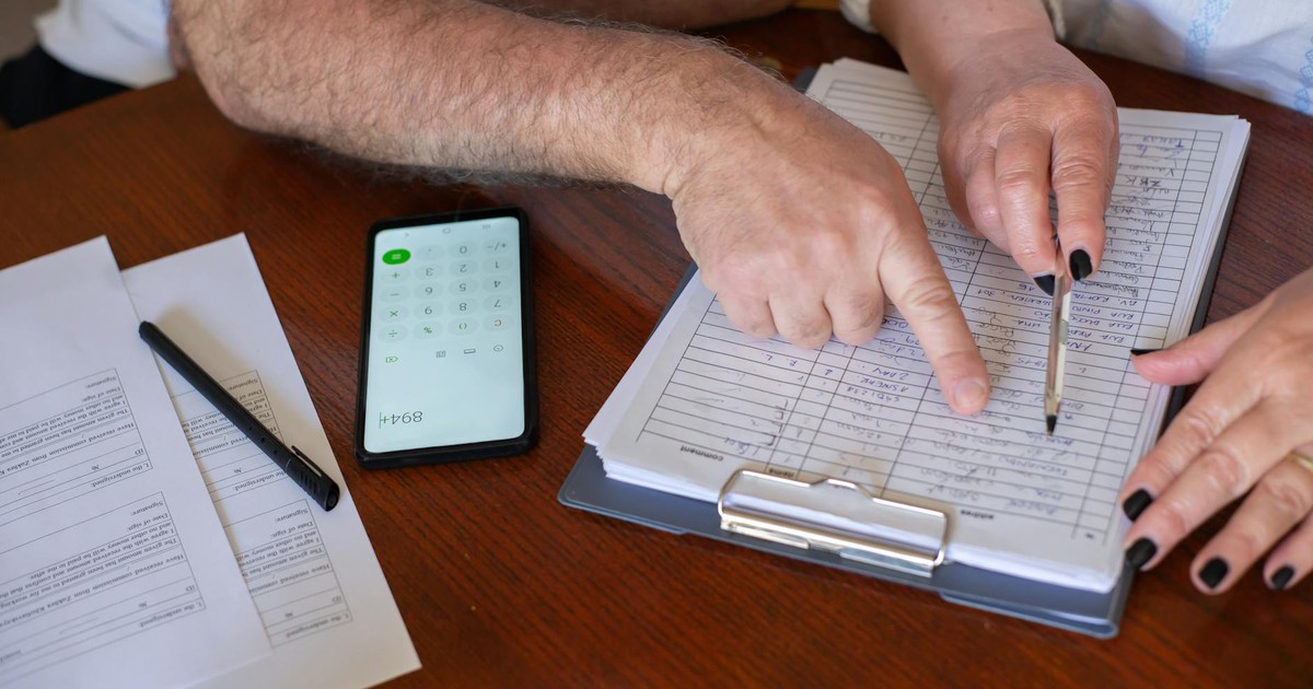 Close-up of hands working on finance planning with documents and a smartphone calculator.