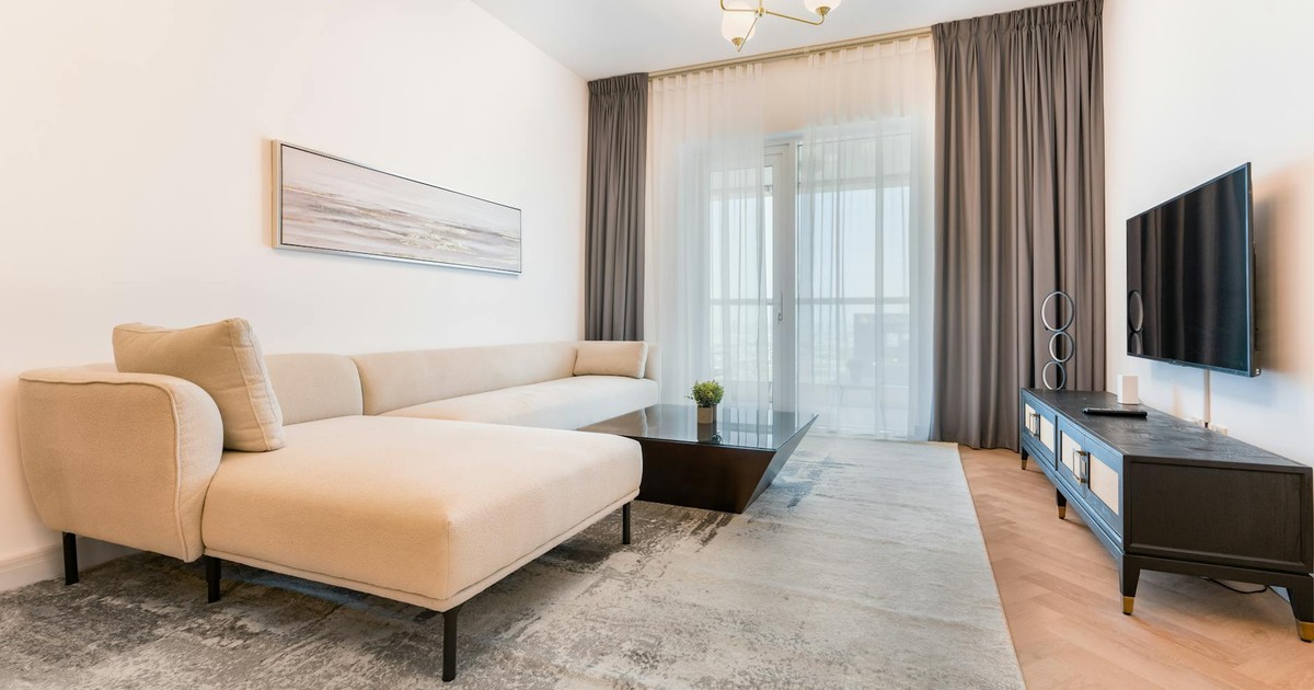 Minimalist living room featuring a beige sofa, coffee table, and TV setup.