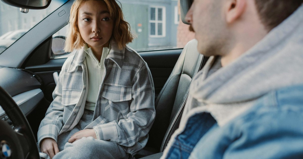 A young couple engaged in a serious conversation inside a parked car, capturing emotional tension.