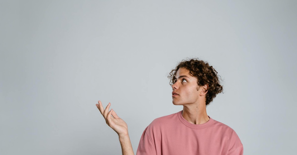 Teenager in a pink t-shirt posing thoughtfully against a plain background, creating ample copy space.
