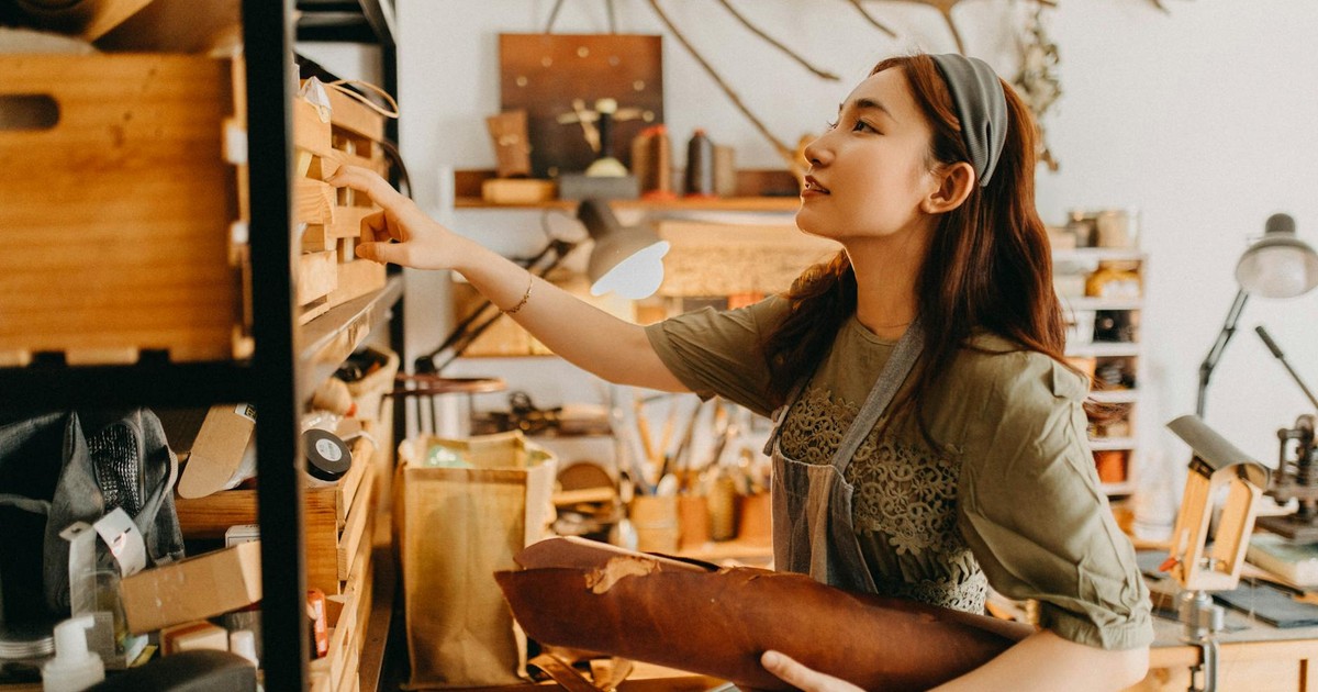 Young artisan woman works in a cozy studio crafting leather goods, showcasing creativity and craftsmanship.