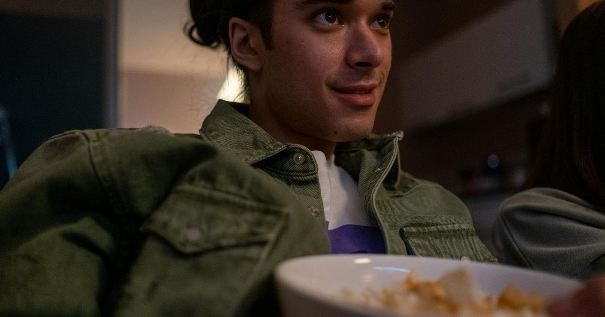 Young man relaxing indoors, watching TV and eating snacks during a cozy movie night.