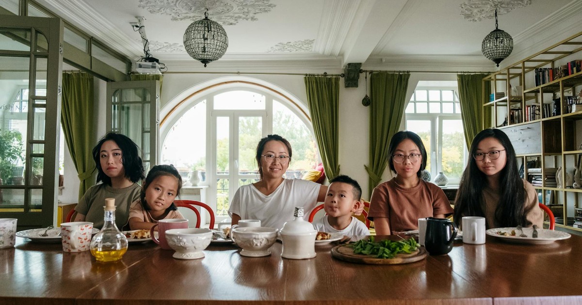 A diverse family enjoying dinner together in a cozy living room setting.