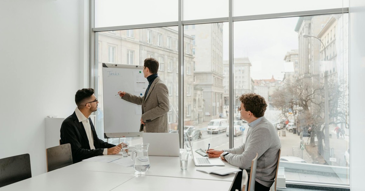 Three professionals engaged in a business meeting in a bright conference room.