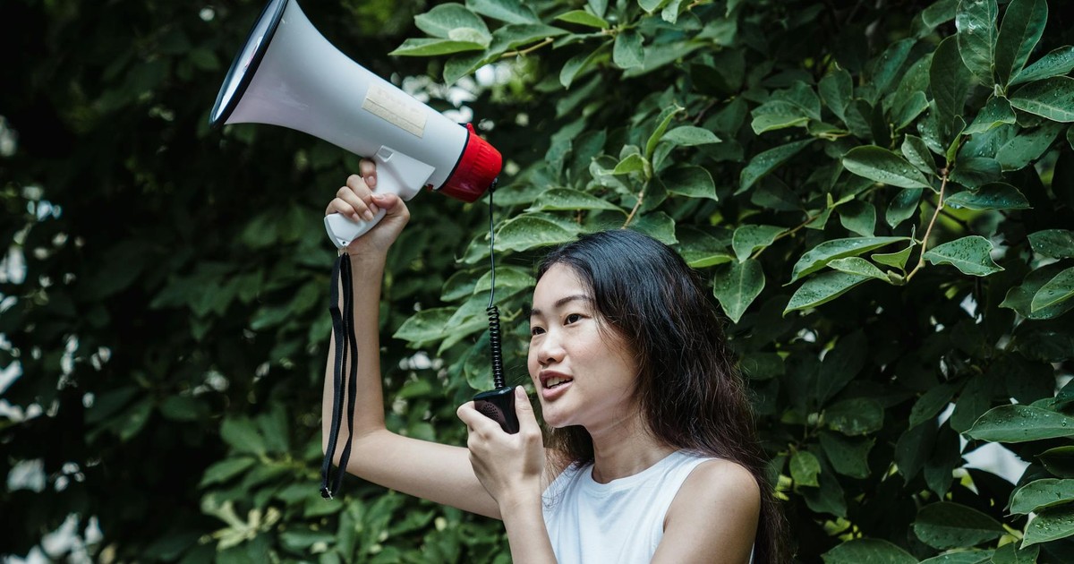 Confident young woman with megaphone at an outdoor rally, advocating for change.