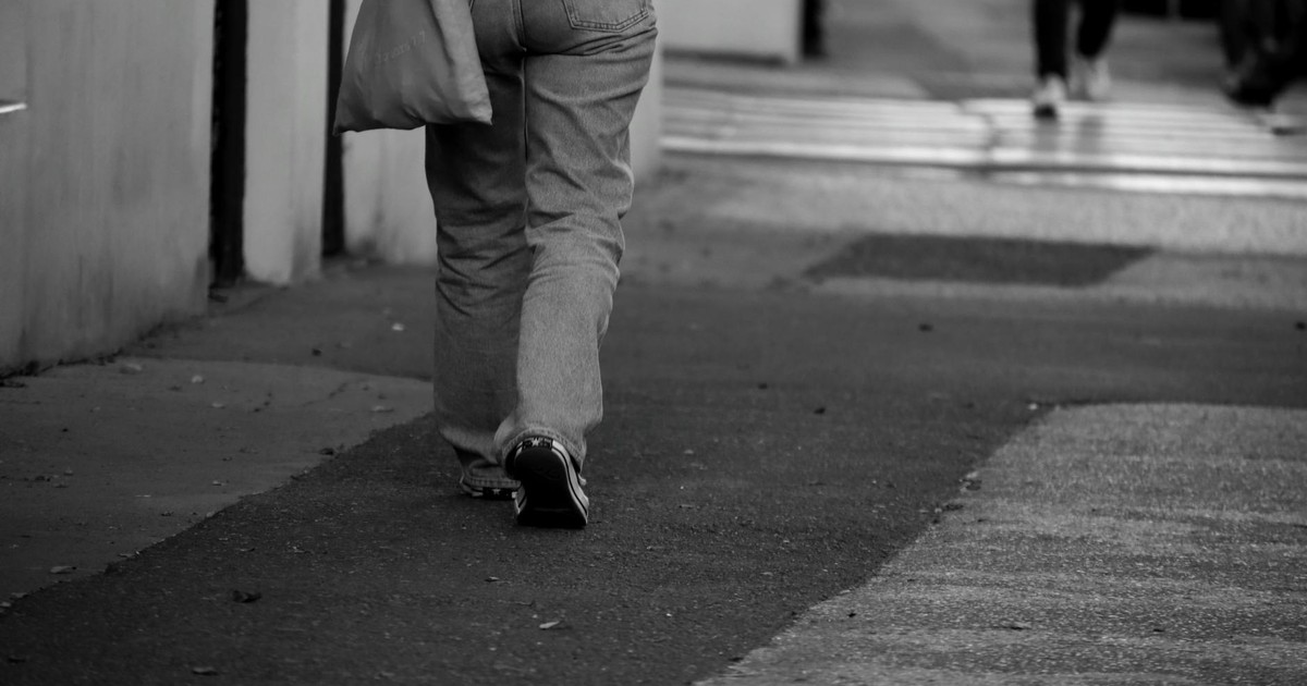 A monochrome photo of a person walking on a city sidewalk in Czechia.